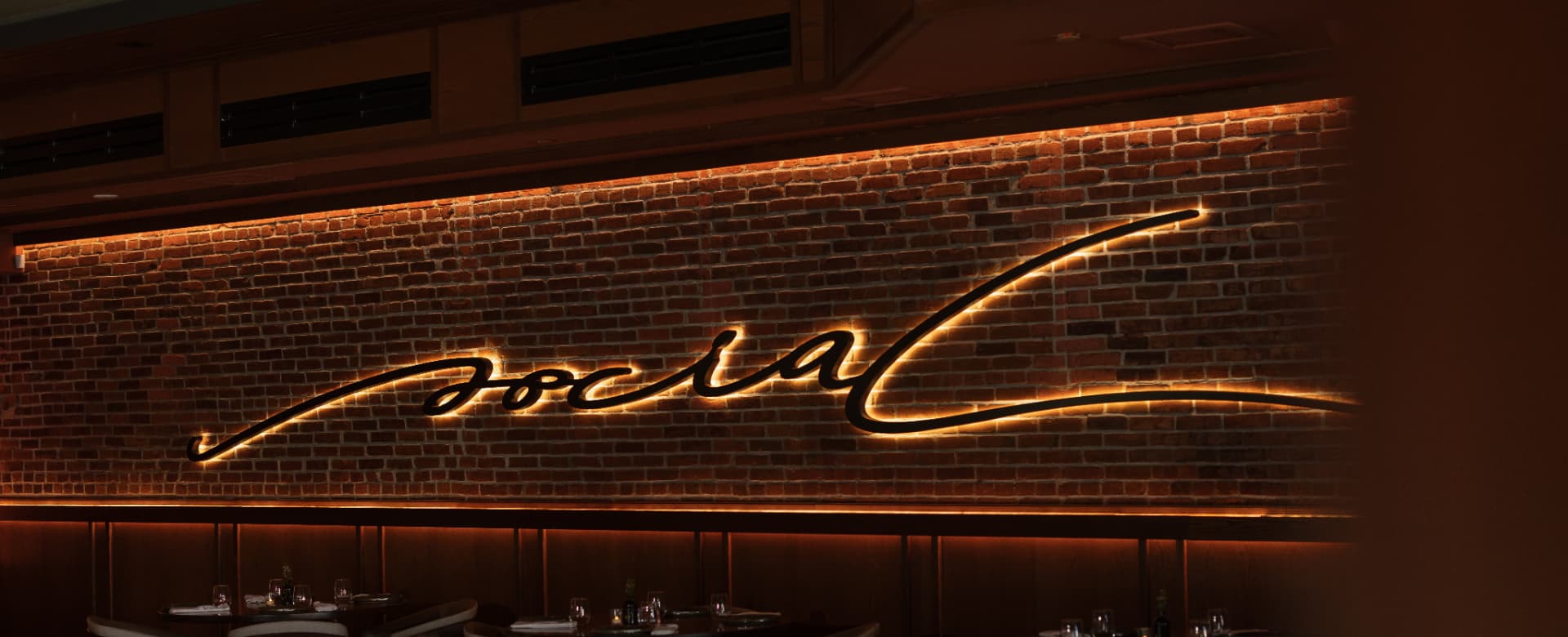 The Social's illuminated script sign above the dining room