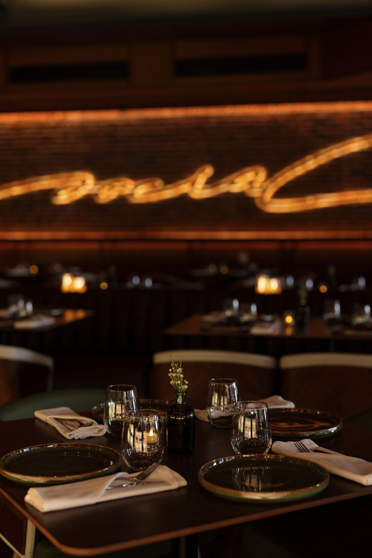 A set dining table beneath The Social's glowing script sign